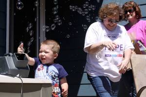 Jackson Young, 3, tries out the bubble machine while Mary Brock, center, and Wendy Hermandorfer try to stand clear of the bubbles at Karla Sharkey&rsquo;s house in Oak Harbor Sunday. The group met for some final preparations for Relay for Life of Whidbey Island, which starts at 6 p.m. Friday. The bubbles will glow in the dark after Friday night&rsquo;s luminary ceremony. Photo by Ron Newberry/Whidbey News-Times