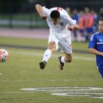 Aram Leyva jumps to kick the ball as Bellevue Christian&rsquo;s John Kim closes in. (Photo by John Fisken)