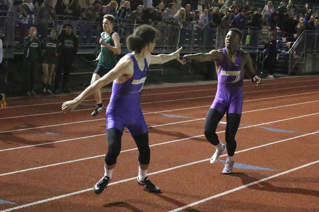 TJ Passmore hands offs to Miguel Guzman in Oak Harbor&rsquo;s win in the 4x400 relay. (Photo by John Fisken)