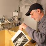 Transforming images of light in a darkroom is part of the artistic touch of black and white photography that appeals to John Olsen. An image of a flower he shot in his studio emerges from the devevloping chemicals.                                Photo by Patricia Guthrie/Whidbey News-Times