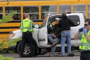 A hit-and-run accident on South Main Street in Coupeville leaves Coupeville&rsquo;s Greg Odle to contemplate what happened while emergency responders with WhidbeyHealth EMS and Central Whidbey Fire & Rescue tend to him as a school bus passes Thursday. Odle was uninjured. The driver who fled on foot was later found in a nearby field and arrested and booked into the Island County jail. Pictured in reflective vests are WhidbeyHealth EMS personnel Greg Behan, left, and Robert May, right. Next to Odle is firefighter/EMT Marvin Raavel. Photo by Ron Newberry/Whidbey News-Times