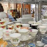 Lion Deanna Rogers organizes shelves of china. Among the dishware for sale is a 16-place setting set of Johann Haviland-Baravia dinnerware in the retired Cinnamon Rose pattern. Photo by Megan Hansen/Whidbey News-Times