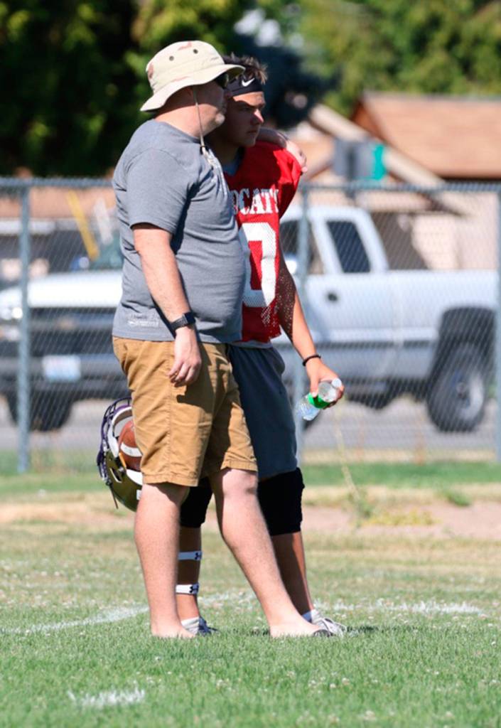 Offensive coordinator Mike Fisher, left, and quarterback Jordan Bell discuss the Wildcats&rsquo; play.