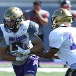 QB Caleb Fitzgerald hands offs to Mac Nuanez. (Photo by John Fisken)