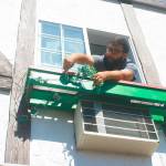 Narno Loza, maintenance worker and housekeeper for Auld Holland Inn, hangs out of a second-story window as he removes worn flower decorations to spruce the place up Monday morning. Photo by Daniel Warn/Whidbey News-Times