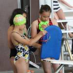Haley Borja, front left, Lola Chargualaf and Kiersten Tyson look over Thurday&rsquo;s practice plan mounted on the back of a paddle board. (Photo by Jim Waller/Whidbey News-Times)