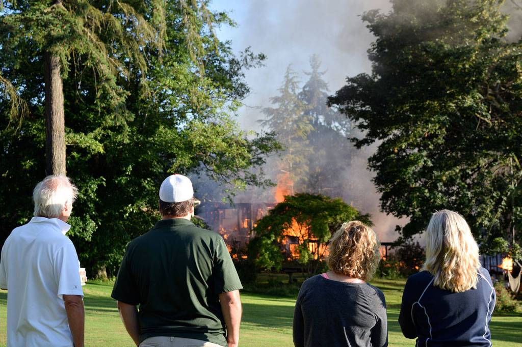 Kyle Jensen / The Record &mdash; Useless Bay Colony residents watch the scene as the house fire dies down. The blaze claimed the home, located on Capt. Vancouver Drive.