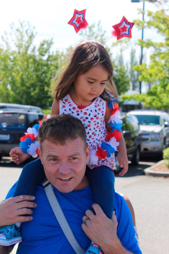 Kaci Groves, 3, gets a ride en route to the parade on the shoulders of Dad, Chris Groves.