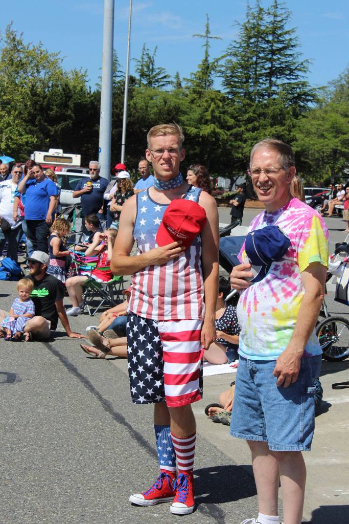 Father and son Matthew (left) and Kevin Turner take off their hats as veterans pass by carrying the American flag.