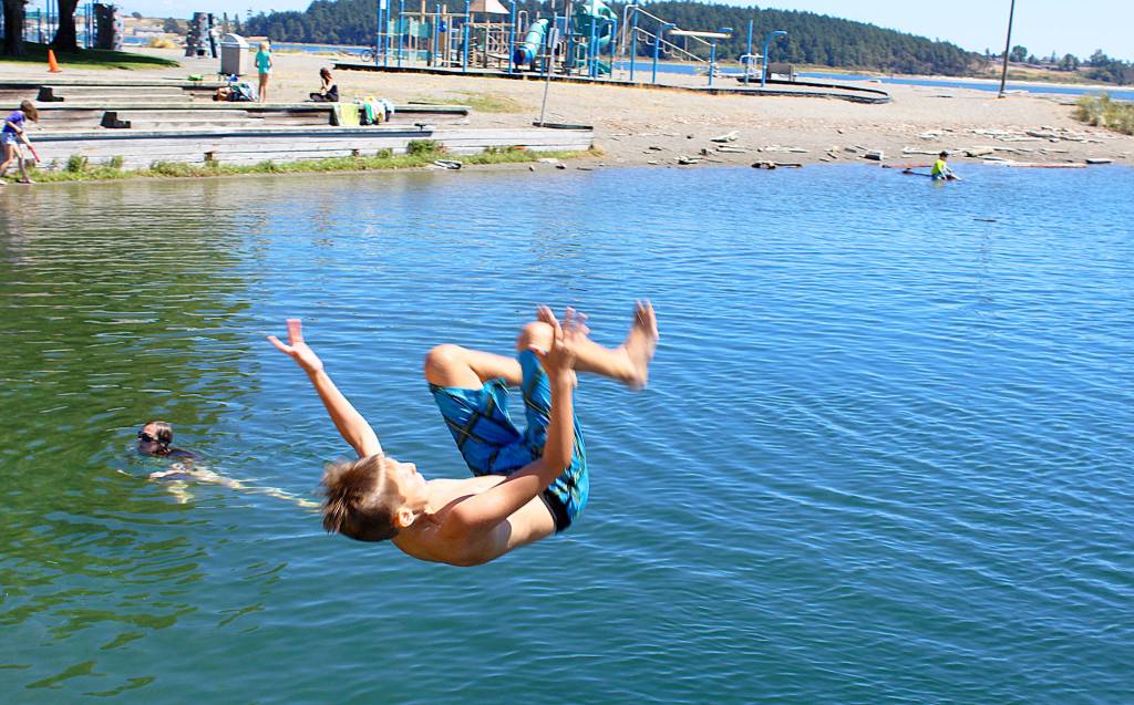 At the Windjammer Park lagoon, Clayton Kester practices his flips. Monday afternoon, many kids (and adults) jumped from the raft and waded in the water or soaked up the sun. &ldquo;I love the hot weather,&rdquo; said Clayton&rsquo;s mother, Jenny Kester. &ldquo;When the sun&rsquo;s out, we&rsquo;re out.&rdquo; Photo by Patricia Guthrie/Whidbey News-Times