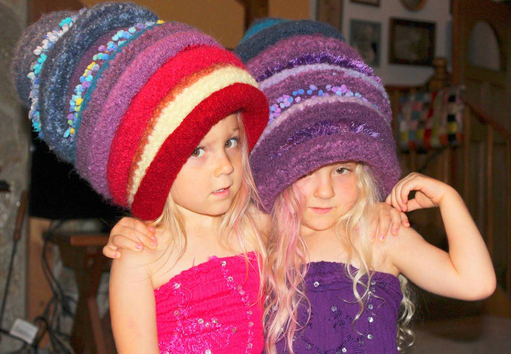 Linda Lee Nicol&rsquo;s granddaughters like to see how many of the colorful hats they can wear when visiting from West Seattle. Modeling Whidbey Woolies&rsquo; hats made from alpaca fiber are twins Audrey (in red dress) and sister, Natalie Nicol. Photo by Patricia Guthrie/Whidbey News-Times