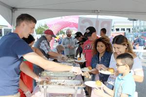 Photo by Patricia Guthrie/Whidbey News-Times                                Volunteers pile up the plates of Diana Benalcazar (wearing jacket) and her relatives at Sunday&rsquo;s Pigfest. The annual Oak Harbor free buffet raised more than $19,000 for charity.