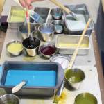 Leslie Stoner dips her brush into wax and colors that are kept on a warming table to stay hot.