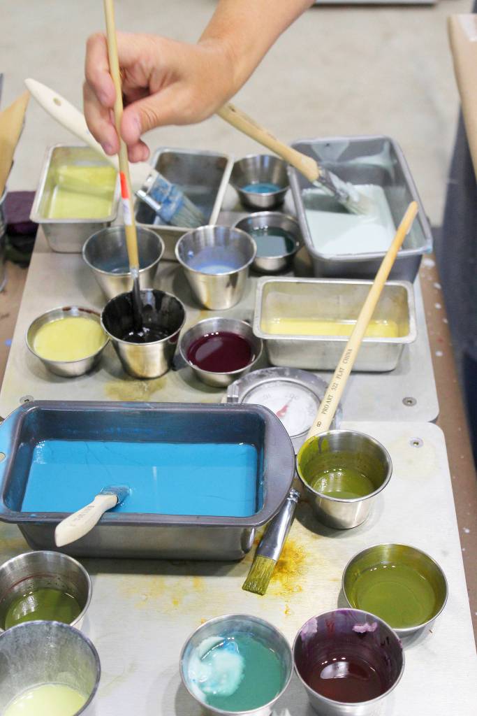 Leslie Stoner dips her brush into wax and colors that are kept on a warming table to stay hot.