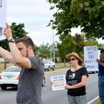 Lori Taylor, her husband Jim Colton (right) and her stepson Ben Colton (left) show signs to passing cars during an assembly against racism Friday outside of Big 5 in Oak Harbor. Taylor organized the event in response to the Equal Employment Opportunity Commission&rsquo;s lawsuit against the company. Photo by Laura Guido/Whidbey News-Times