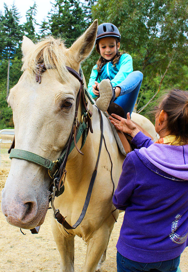 Aida Daly saddles up on Tango with instructions from Sue Landusky, owner of Stride &lsquo;N Glide. Daly was treated to a birthday trail ride with her family by her grandmother. Photo by Patricia Guthrie/Whidbey News-Times