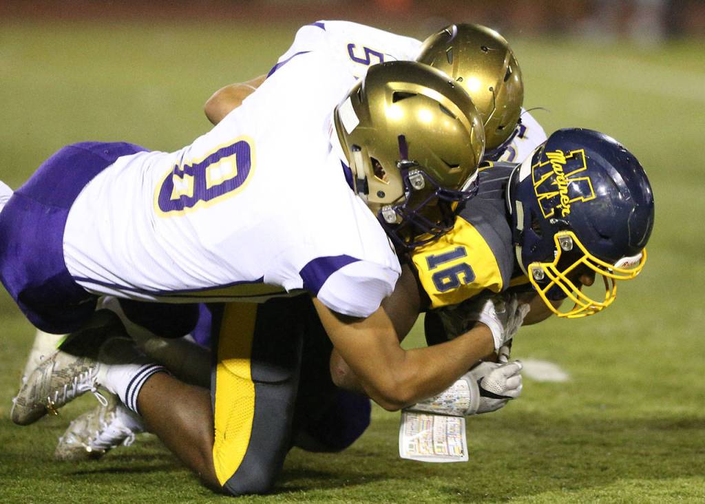 Darian Matsushita (8) and Isaac Gomez stop Mariner&rsquo;s Amory Brown. (Photo by John Fisken)