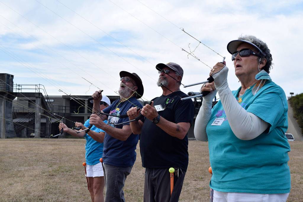 Kyle Jensen / The Record &mdash; Festival chair Lisa Root (right) joins others from Whidbey Island Kite Fliers in a team flight Monday afternoon.