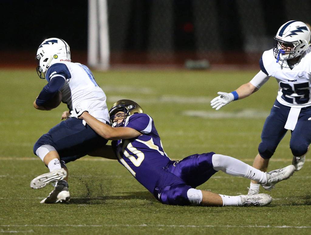 Oak Harbor&rsquo;s Mac Carr drags down Squalicum&rsquo;s quarterback Spencer Lloyd. Later in the game, Carr intercepted a Lloyd pass to seal the win. (Photo by John Fisken)