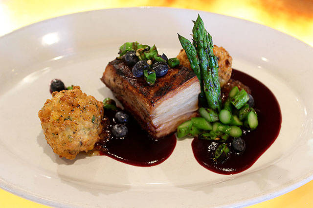 A pork belly entree with a bittersweet blueberry sauce, pickled blueberries, roasted corn fritters and charred asparagus.