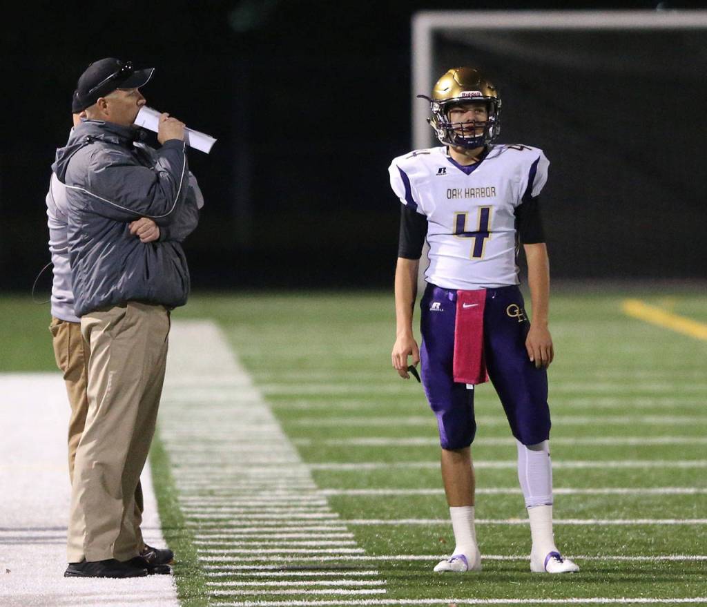 Oak Harbor quarterback Jordan Bell, right, listens to the play call from offensive coordinator Mike Fisher.Photo by John Fisken