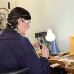 Rosalie Gale photo                                Above: Foamy Wader owner Alexa Allamano works on one of her nautical-themed pieces of jewelry in her Langley storefront. Inset: Allamano makes home decor in addition to jewelry. In this piece, 52 gemstones are tethered to vertical chains and suspended in the center of a brass oval.