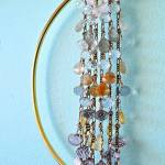 Alexa Allamano photo                                Allamano makes home decor in addition to jewelry. In this piece, 52 gemstones are tethered to vertical chains and suspended in the center of a brass oval.