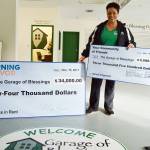 Kristiina Miller holds up two large checks she received during filming of Returning the Favor, a new show on Facebook with Mike Rowe. Millers Garage of Blessings will be featured on the show in February. Photo by Laura Guido/Whidbey News-Times