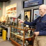 Wil Shellenberger, president of the PBY Museum Foundation, points to a wall display of newspaper from the WWII era. Photo by Patricia Guthrie/Whidbey News-Times