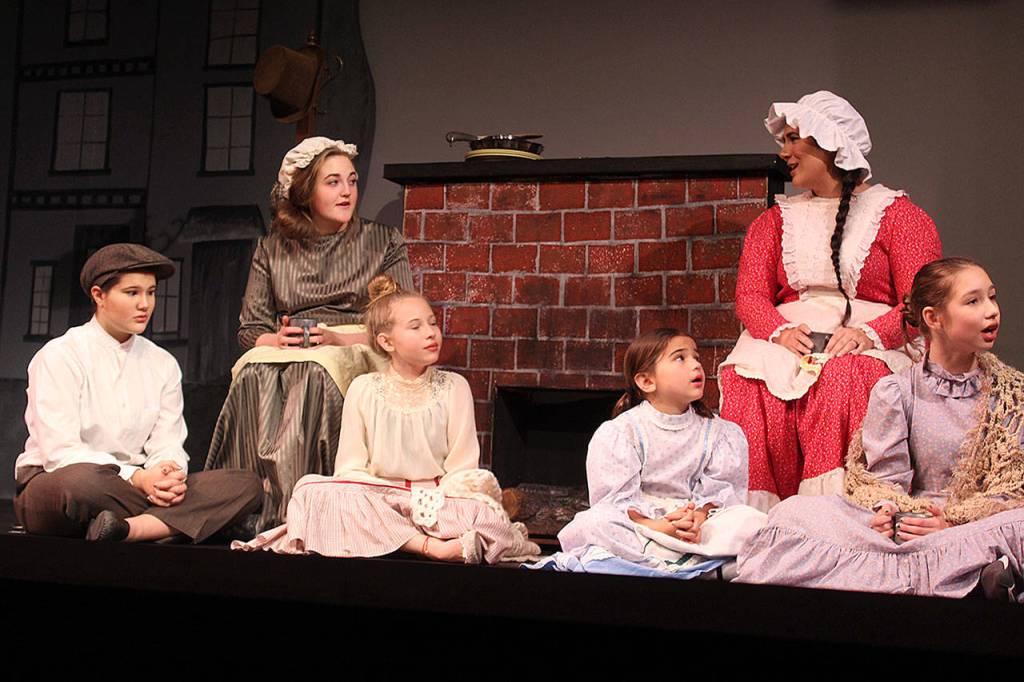 <address>Actors portraying the Cratchit children, some making their debut on stage, gather at home with Mrs. Cratchit. Left to right: Rhiannon Chapman, Gabrielle Eatonon (on stool), Ashley Coker, Ellie Collette, Diana Walker, Cheyenne Henson. </address>