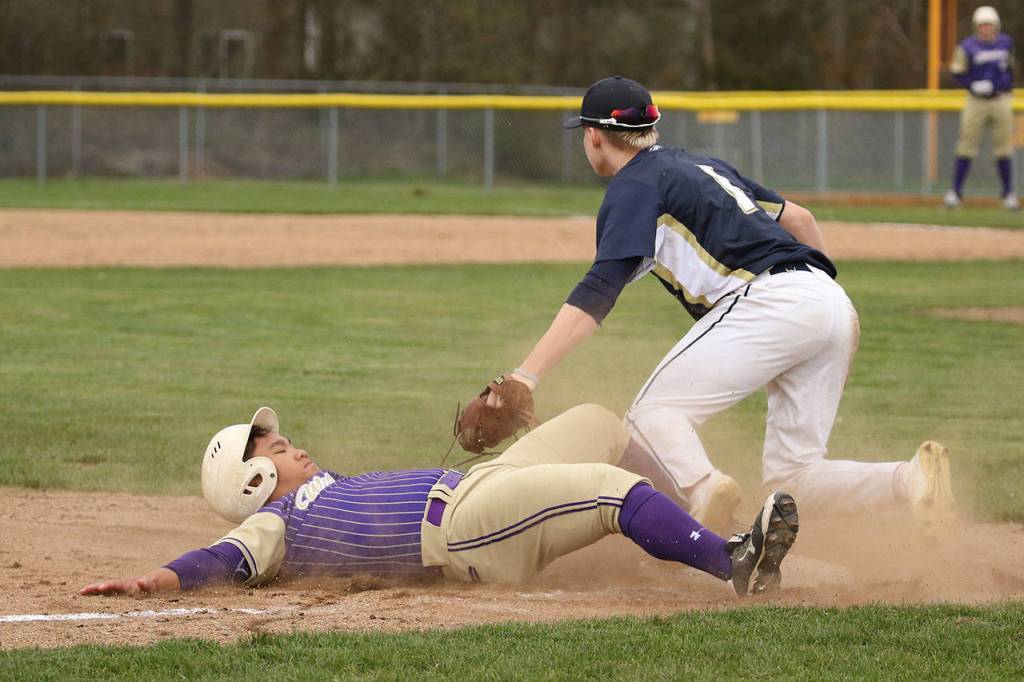 Oak Harbor Donnie Kloewer slides into third base ahead of the tag by Arlingtons Camden Anderson.(Photo by John Fisken)