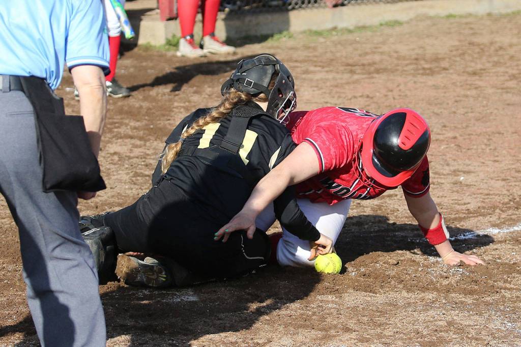 Sarah Wright reaches for home play in the win over Meridian. Wright was safe as the ball slipped away from catcher Audrey Mark.(Photo by John Fisken)