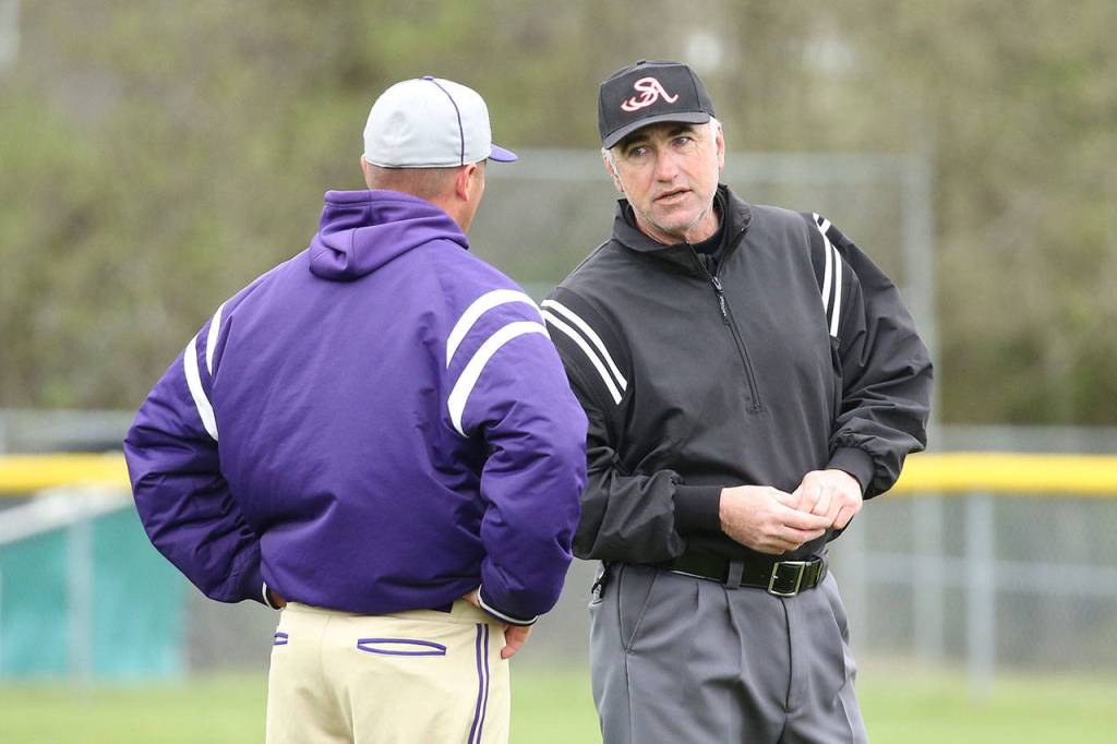 Oak Harbor coach Cody Anderson discusses a play with one of the umpires Wednesday. Several questionable calls hurt the Wildcats.(Photo by John Fisken)