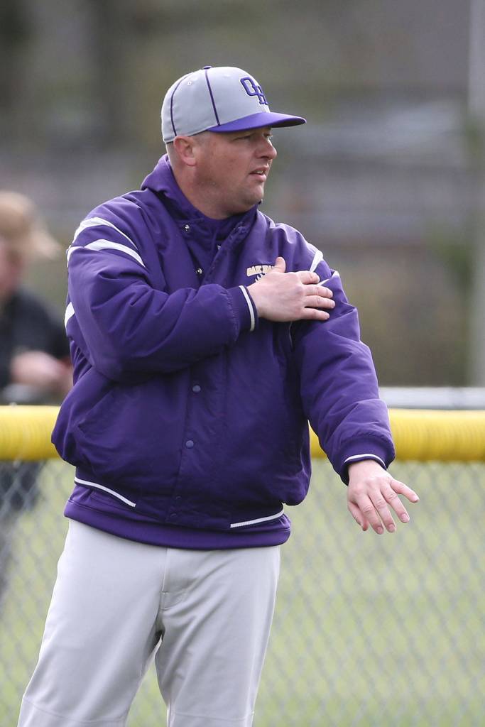 Coach Cody Anderson passes along a signal to an Oak Harbor baserunner. (Photo by John Fisken)