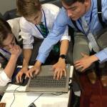 From left, Casey Towsley, Ben Gasper and Cullen Wood use their unique method to run a 15-minute hotel business simulation at the DECA international championship in Atlanta, Ga. The team was able to take first place in the last five seconds. Photo provided