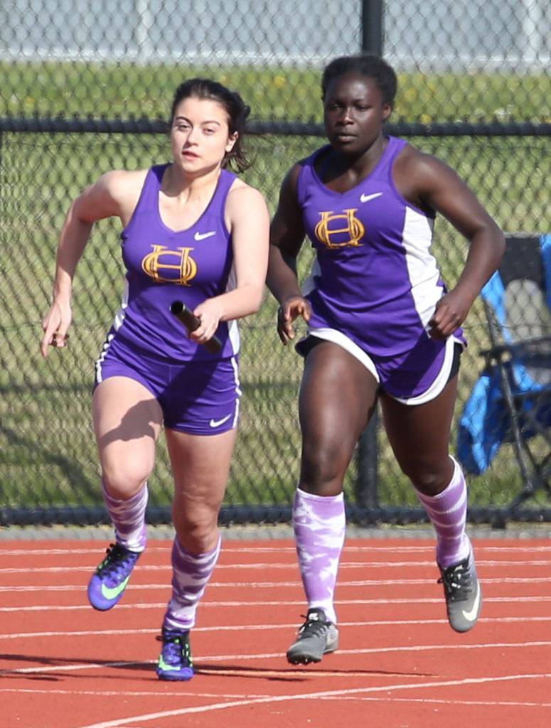 Alora Caillier, left, receives a hand off from Maria Dailey in the 4x100. (Photo by John Fisken)