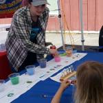 Jackie Wenala from the Skagit Fisheries Enhancement Group explains to three-year-old Ezra Malloy the stages of a salmons lifespace and what they need to survive.