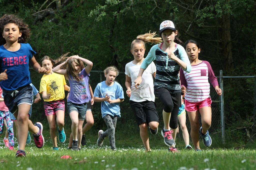 Oak Harbor Elementarys Gabriella Lavolpa, far left, and Hillcrests Aleera Kent, cap, lead a group around the first turn.(Photo by Jim Waller/Whidbey News-Times)