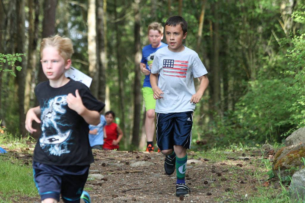 Caleb Zarraonandia (flag shirt) jogs through the woods in Thurdays race.(Photo by Jim Waller/Whidbey News-Times)