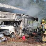 Photo by Jessie Stensland / Whidbey News-Times                                A firefighter sprays down an RV that caught fire at a North Whidbey home Tuesday.