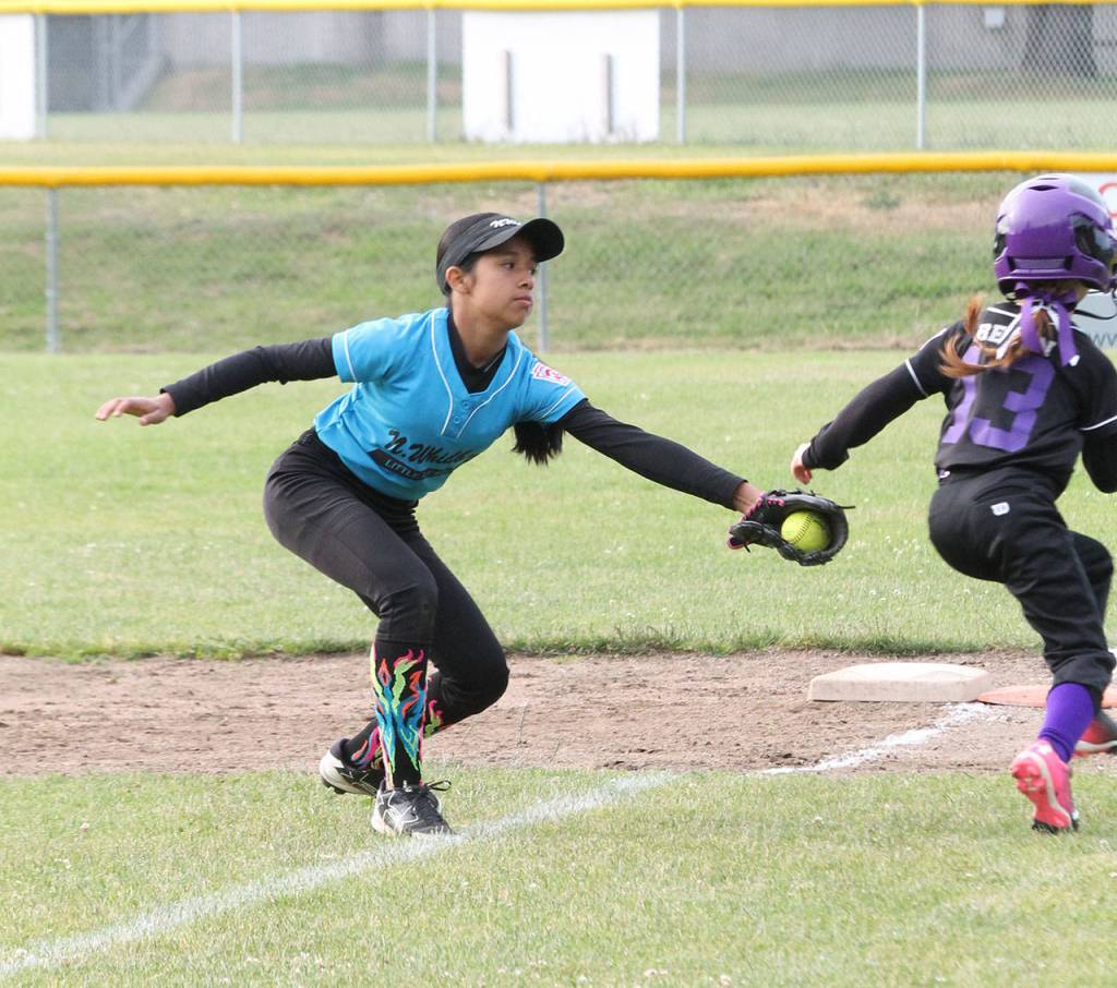 Blue Dragon first baseman Jaydin Lopez reaches for an out on the Bat Busters Mia Regan.(Photo by Jim Waller/Whidbey News-Times)