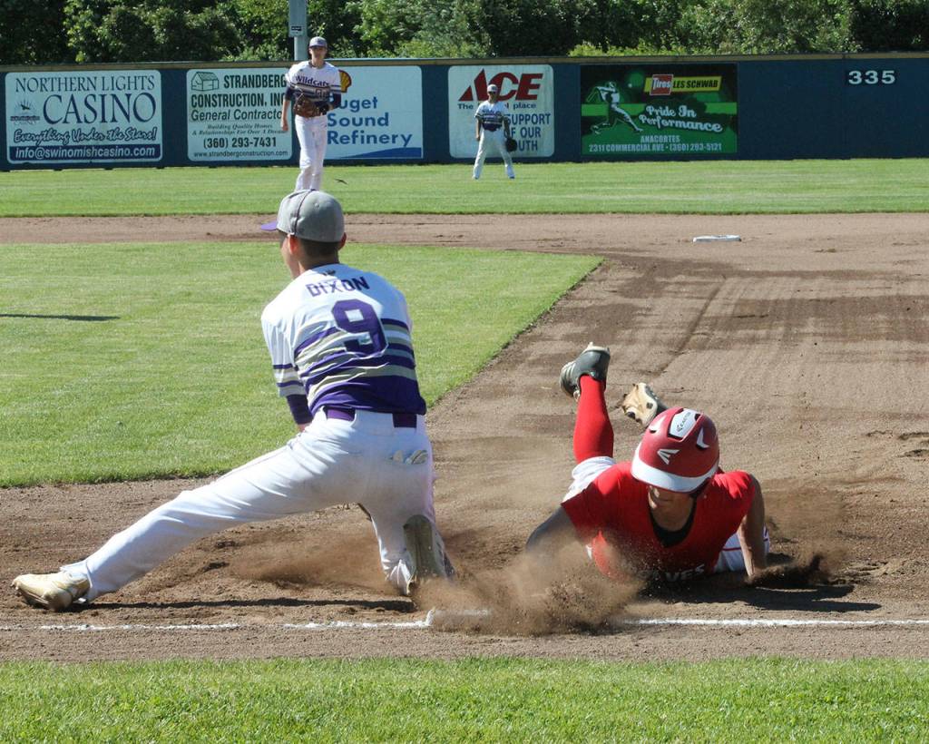 Hunter Smith slides back into first base covered by Andrew Dixon on a pickoff attempt.(Photo by Jim Waller/Whidbey News-Times)