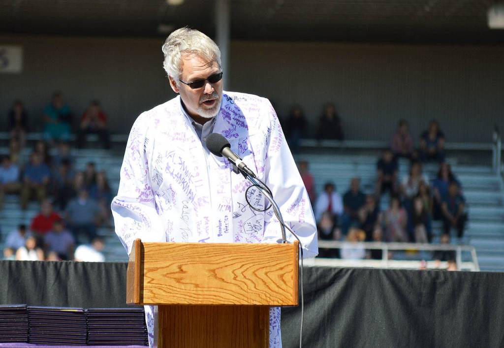 Oak Harbor High School Principal Dwight Lundstrom gives parting advice to the graduates during commencement Saturday while wearing a custom robe with the signitures of the class of 2018. Photo by Laura Guido/Whidbey News-Times