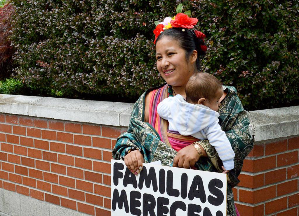 Sandra Chitacapa, holding her 5-month-old son Alejandro, spoke at Saturdays rally in Coupeville. Chitacapa is an Oak Harbor resident who came to the United States from Ecuador. She told the story of her father who was an undocumented immigrant who became a citizen. Her sign reads Familias Merecen Estar Juntas, which translates to families belong together.
