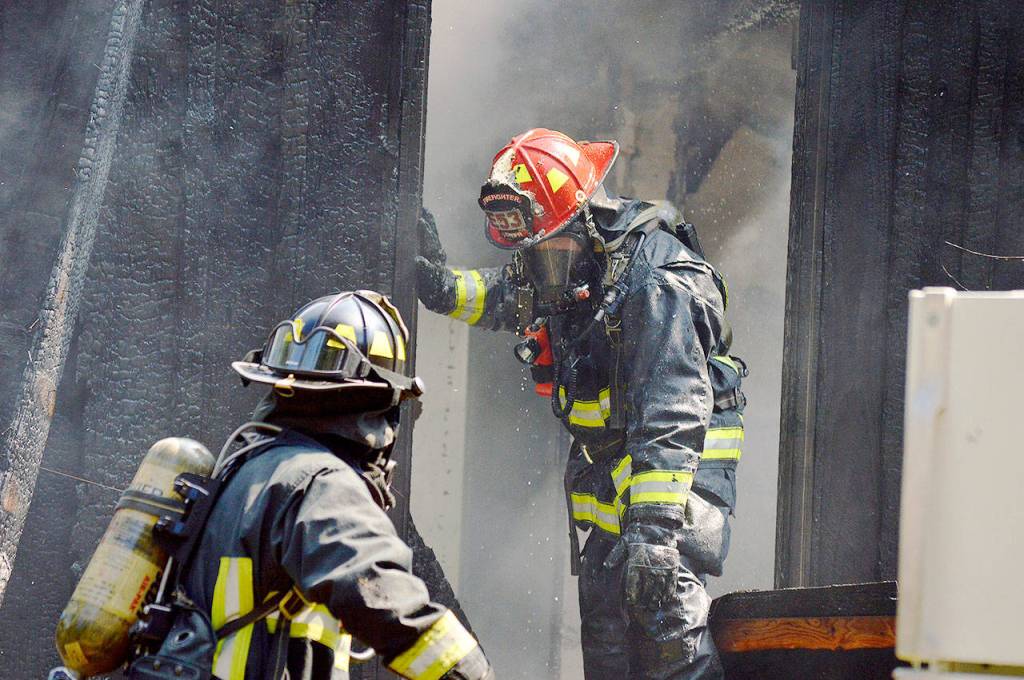 Lt. James Meek, of Central Whidbey Island Fire and Rescue, stands in the doorway of a house on Classic Road destroyed by a fire Wednesday. Photo by Laura Guido/Whidbey News-Times