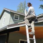 Photo by Dave Felice / Whidbey News Group.                                Electrician Kyle Collins measures mounting rails for new solar panels atop the home of Bob and Gladys Shepard.