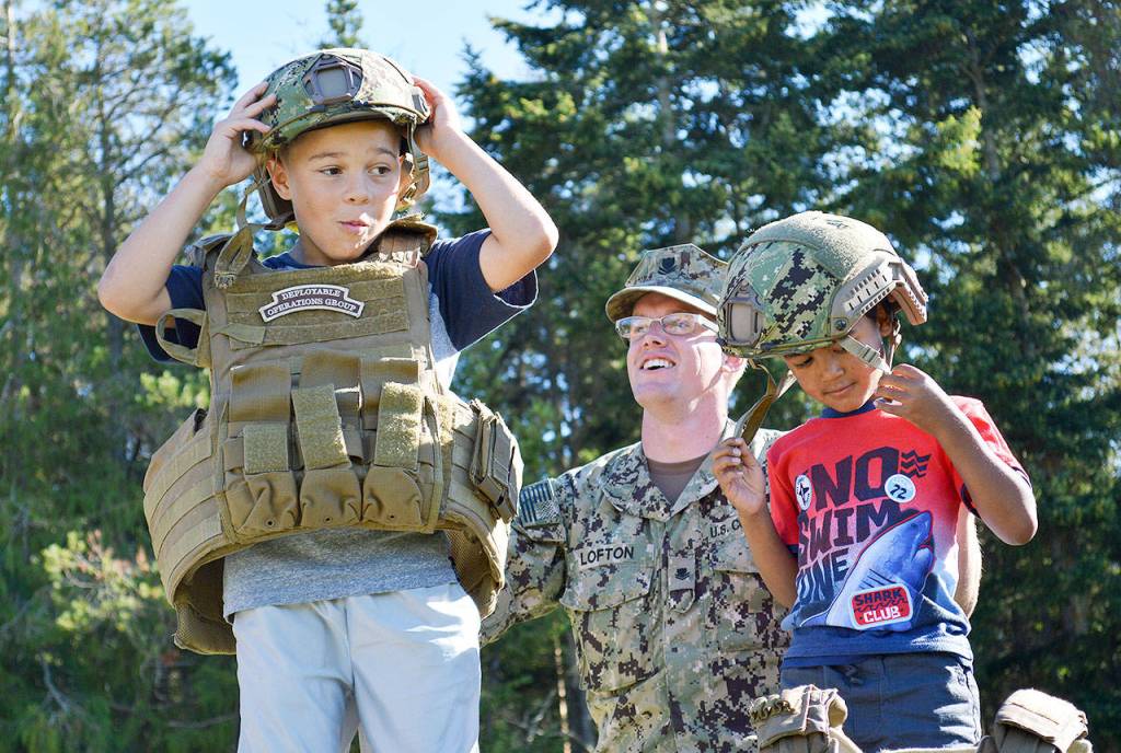 Eight-year-old Isaiah Anderson, left, and 5-year-old Jumar Davis try on Coast Guard equipment with the help of Petty Officer Nate Lofton Tuesday night at Fort Nugent. Photo by Laura Guido/Whidbey News-Times