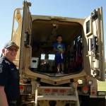 Photo by Maria Matson/Whidbey News-Times                                Four-year-old Atreyu Corpuz of Oak Harbor smiles as he stands inside a MRAP vehicle. Oak Harbor Police Department Chaplin Ron Lawler made sure he entered and exited the vehicle safely.