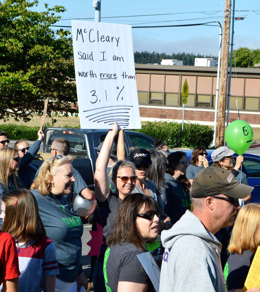 Lindsey Smith, a teacher at Oak Harbor Intermediate School, holds up a sign at a union rally Tuesday morning. Bargaining had reached a stalemate over a perceived cap in salary increases that has since been resolved, according to the district and union members. Photo by Laura Guido/Whidbey News-Times