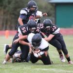 Coupeville defenders Alex Turner (55) and Gavin Knoblich (33) smother a Vashon Island ball carrier as Isaiah Bittner closes in.(Photo by John Fisken)